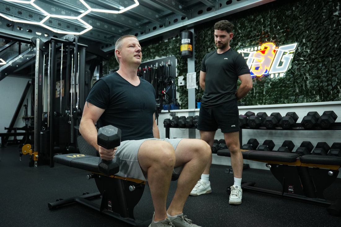 Klant traint met een dumbbell onder begeleiding van Danny
